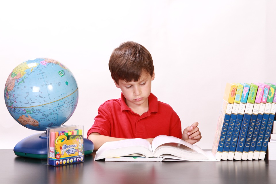 Reading Youngster Framed By A Globe, Highlighters, And Volumes Of An Illustrated Anthology