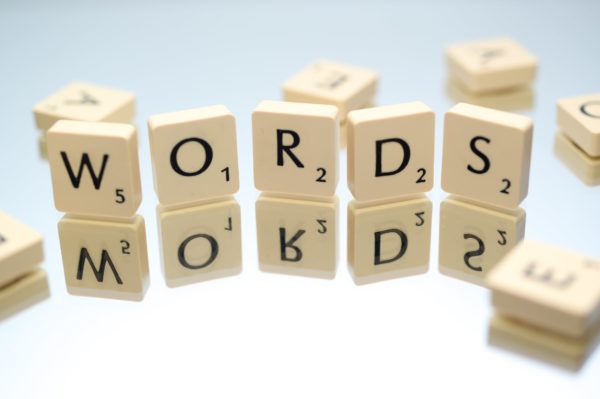 Scrabble® Letter Tiles Stood Vertically On A Mirror, Spelling Words