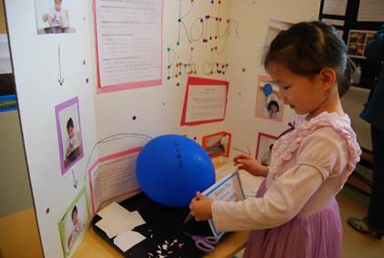 A little girl setting up for her science fair project at living montessori.