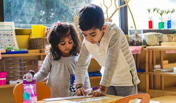 Montessori Preschool Students Work Together On Writing Activity